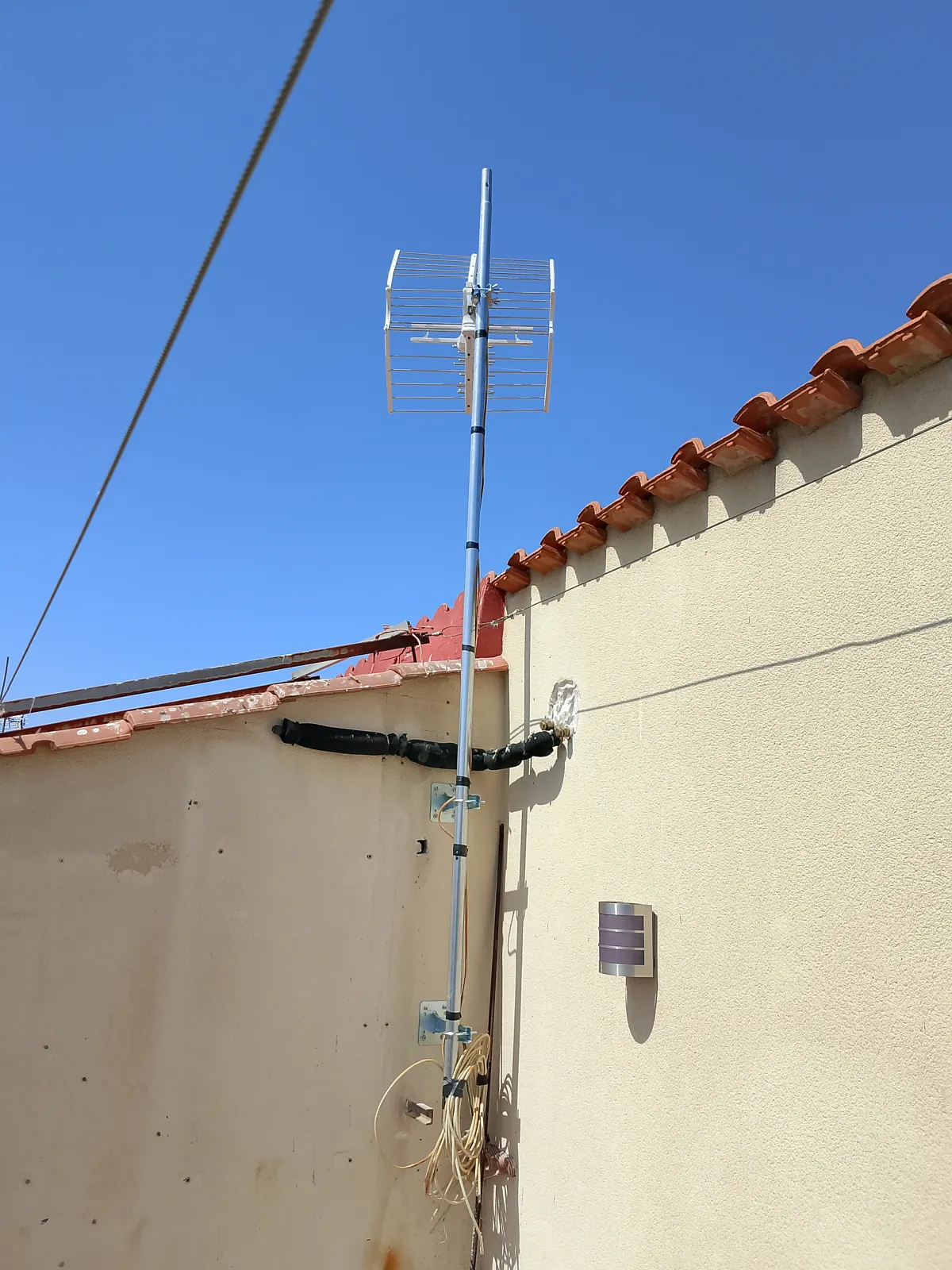 Mástil de antena fijado a la fachada.